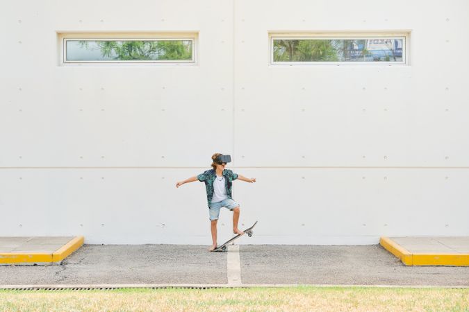 Active preteen skateboarder in VR glasses on street