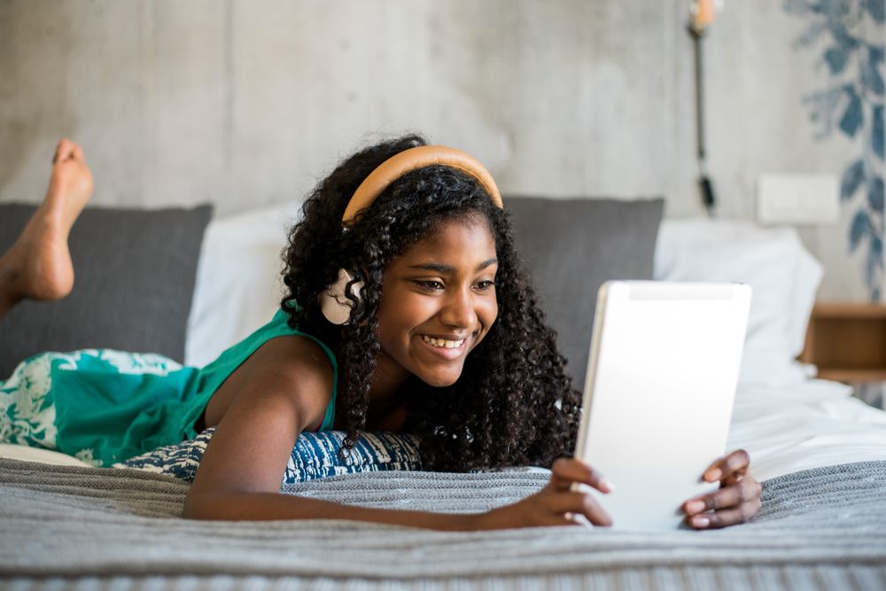 Black teenage reading a book on bed