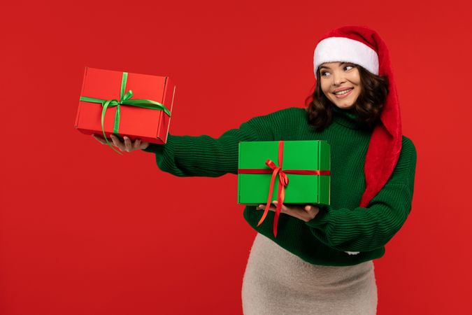 Smiling woman in Santa hat holding Christmas gift boxes.