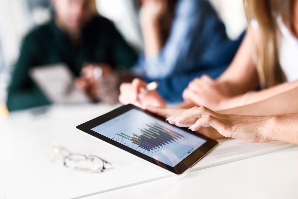 Close up of woman’s hands with group working on tablet