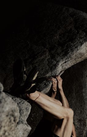 Man practicing rock climbing among large rocks in a forest