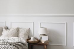 Bedside table in neutral room with tray of coffee, lamp and blank card