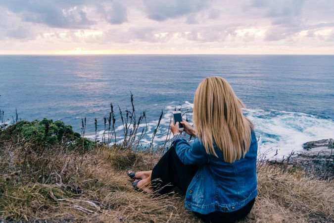Female tourist taking shot of sea in twilight