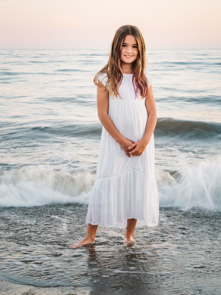Smiling girl standing on seaside among waves