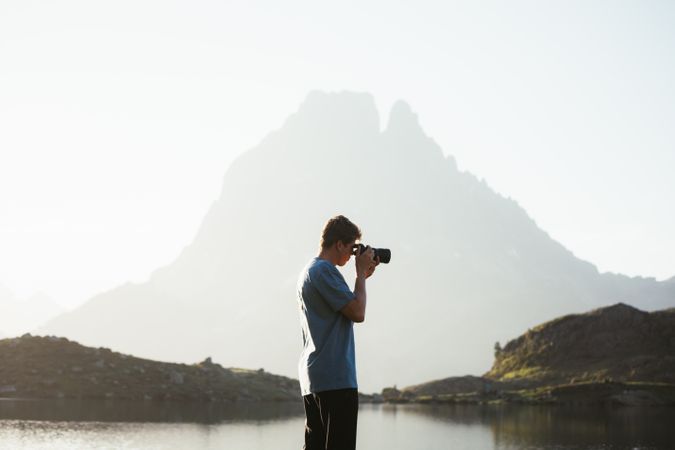 Unrecognizable man taking photo of mountain landscape