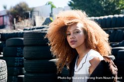 Close up shot of young woman with afro and freckles outside in front of tires 5ngZm4