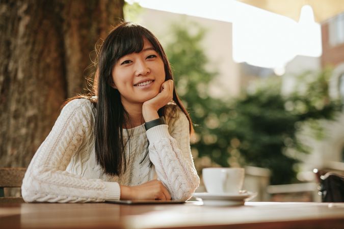 Shot of attractive girl sitting at cafe table and smiling