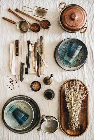 Vintage kitchen utensils artfully arranged on beige tablecloth, vertical composition