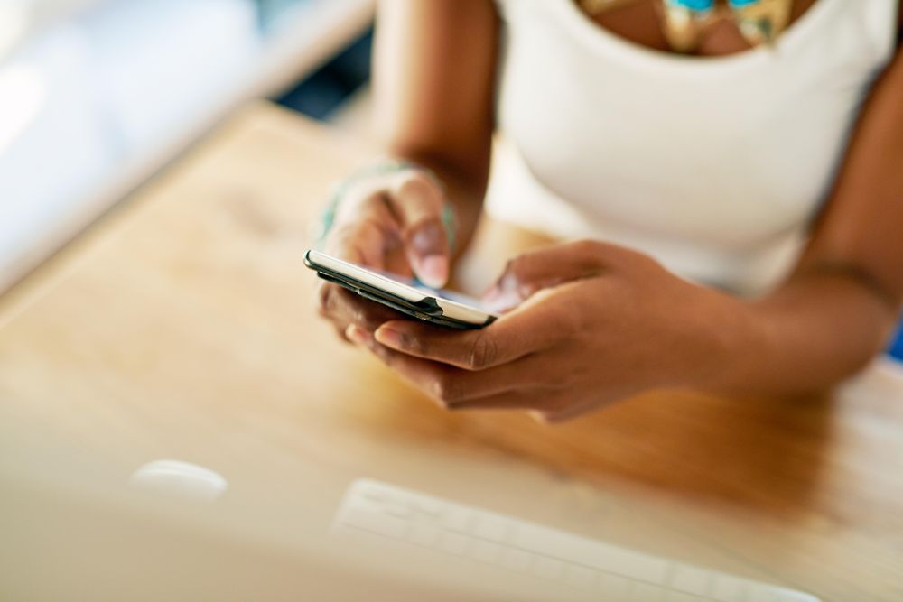 Close up of female hands texting at wooden desk