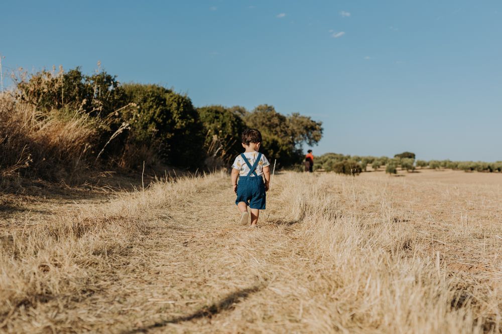 Back of child in overalls walking in a field during the fall