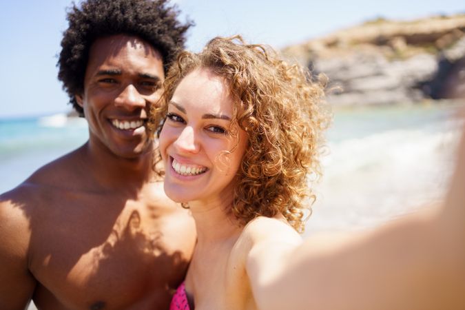 Selfie of smiling diverse couple near ocean
