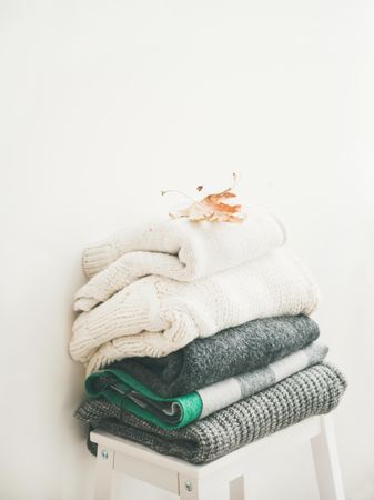 Pile of clean, folded sweaters on light background, square crop, copy space