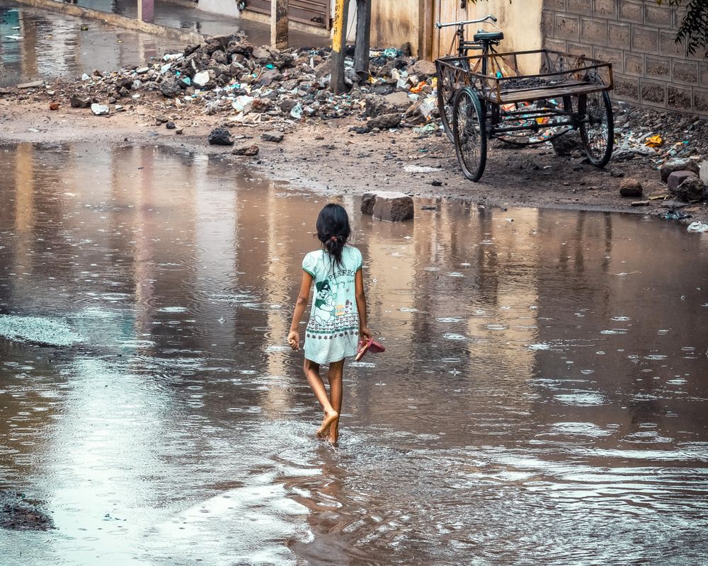 Girl waking on shallow water on the road during daytime