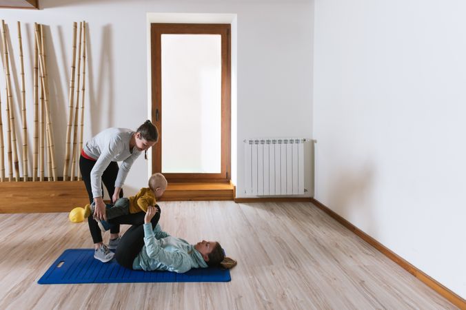 Fitness instructor helping mother with push ups