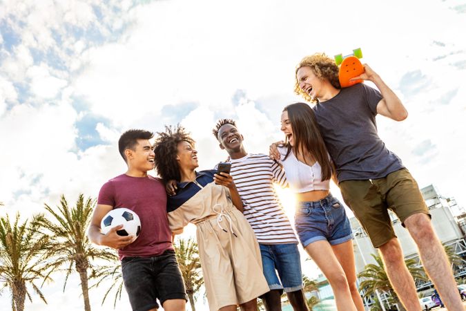 Friends happily walking together with skateboard and soccer ball