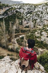 Woman with backpack on high cliff