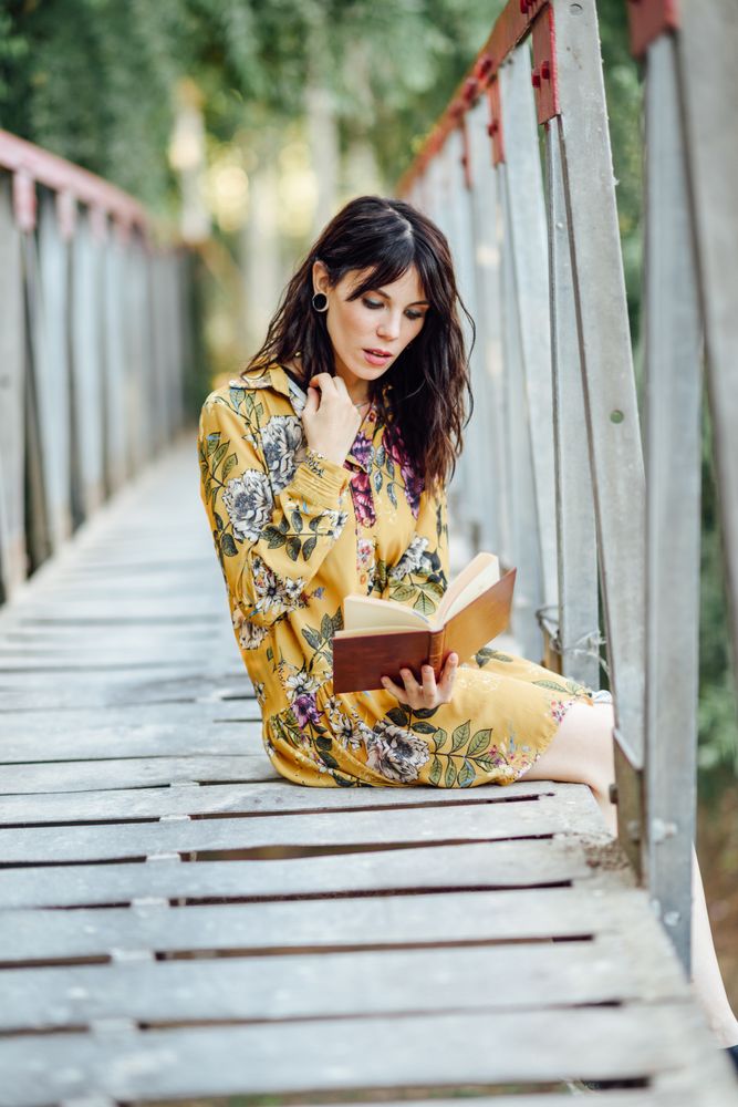 Female sitting on a rural bridge enjoying reading
