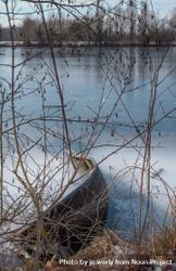 Boat on frozen lake pictured through branches 0ypJqb