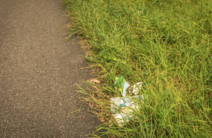 Trash on the side of the road in the grass