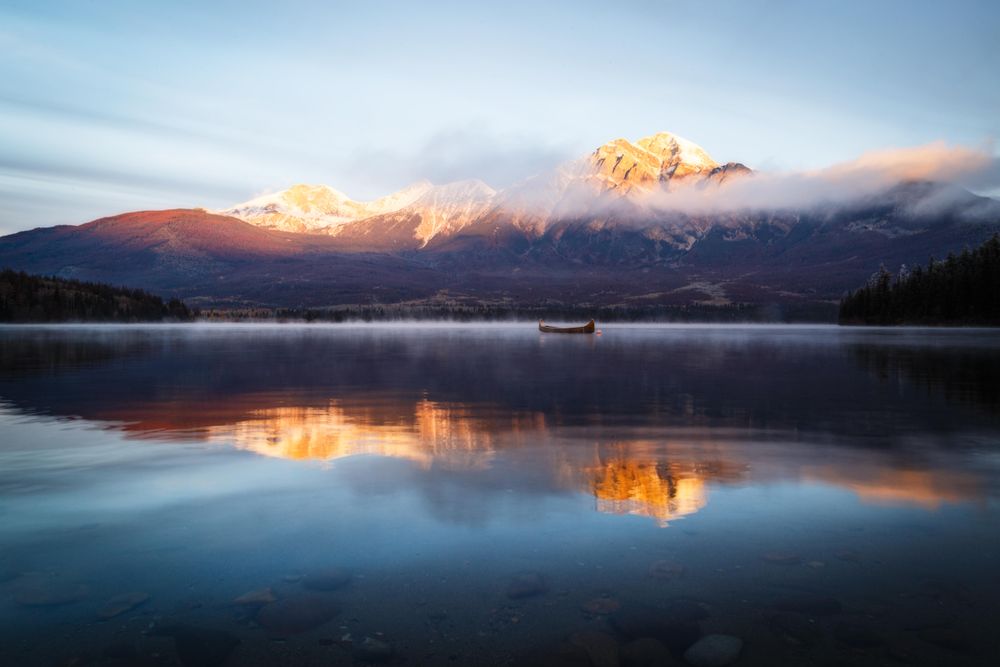 Boat on still water near mountain during sunset
