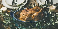 Centerpiece of roast chicken with decorative branches, candles, wide composition