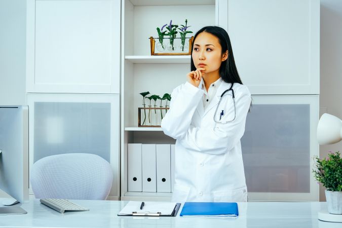 Asian doctor considering a question in her office