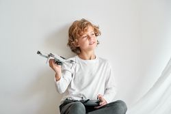 Content child with toy drone dreaming near wall
