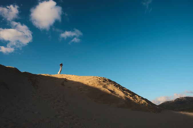 Sun lighted sandy hill with blue sky and white cloud