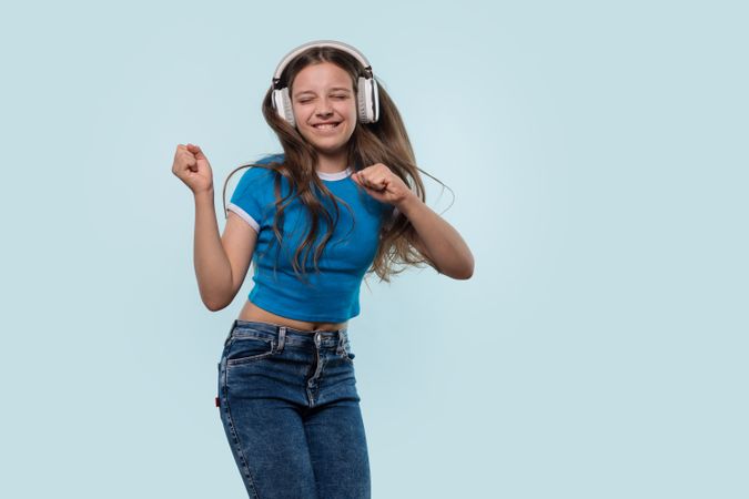 Girl wearing headphones dances joyfully while listening to music.