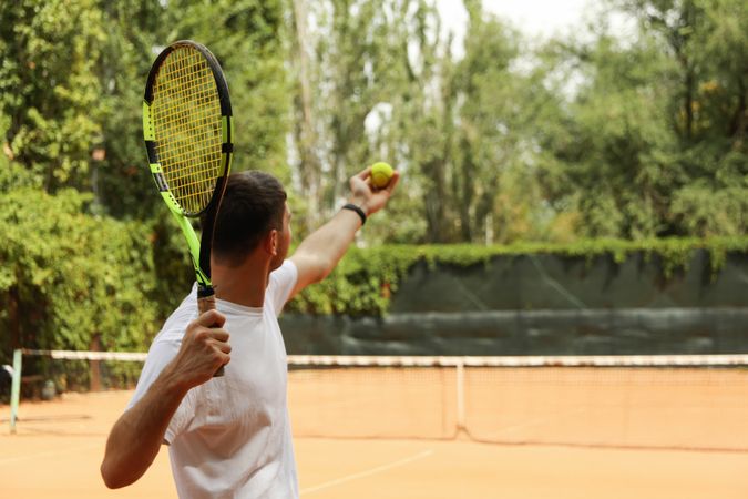 Young man in white t-shirt serve the tennis ball