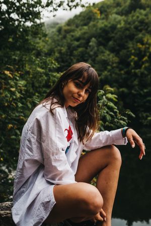 Woman sitting on rock near lake and mountains