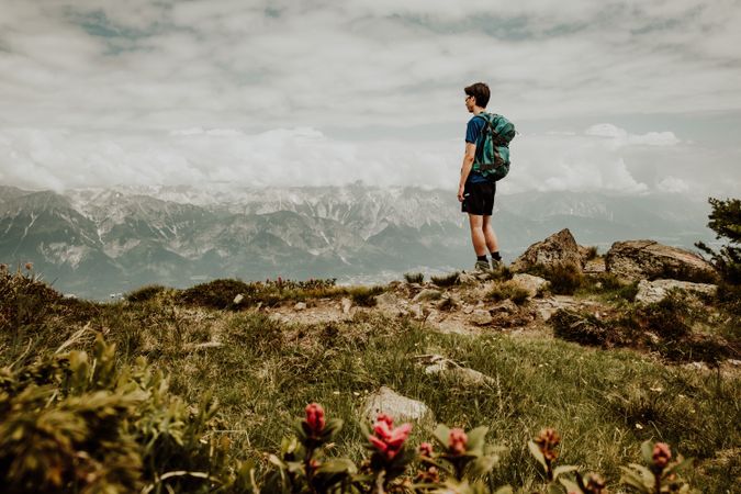 Man with backpack standing on hill looking at mountains