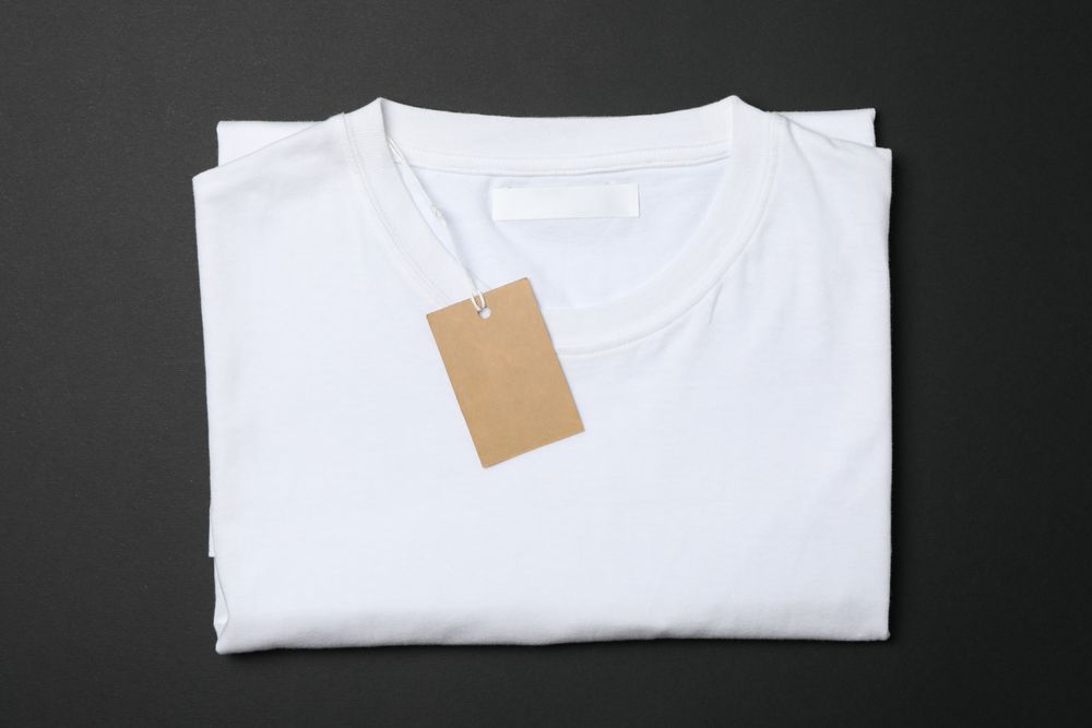 Folded blank plain t-shirt with tag on dark background, space for text