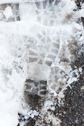 Shoe prints on wet snow on asphalt road