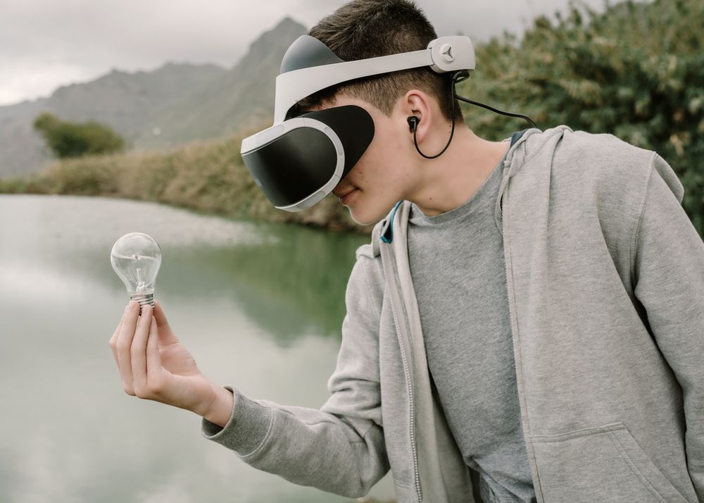 Young teenager with virtual reality glasses holding a light bulb