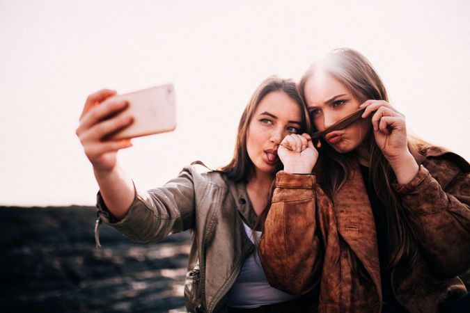 Two young women taking a silly selfie outside