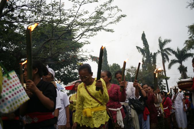 Group of mature Indonesian Hindu women with torches marching during Nyepi day