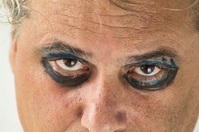 Middle aged man's serious eyes with dark and blue eyeshadow