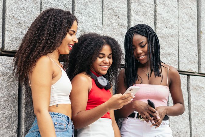 Connected young people: female friends using smartphone in the city