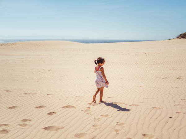 Cute little girl playing with sand at beach