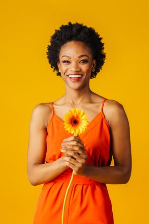 Beautiful Black woman holding a single daisy