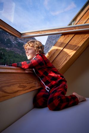 Smiling boy looking out window in mountain hotel