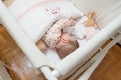 Baby sleeping in a cot with pacifier and toy