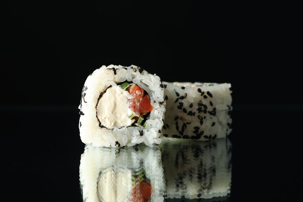 Delicious sushi rolls on dark mirror background. Japanese food