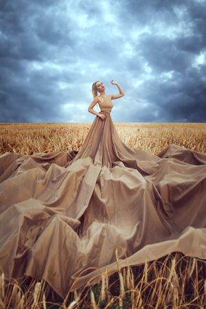 Woman in big brown dress standing in wheat field