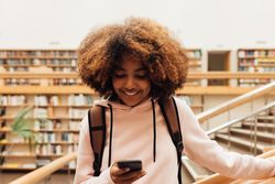 Female student smiling while texting in library