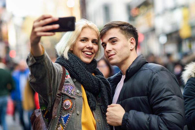 Female taking selfie with her male friend in UK street