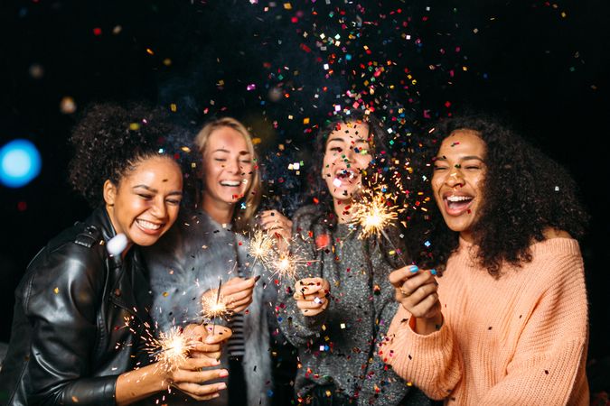 Multi-ethnic group of happy women with sparklers at party