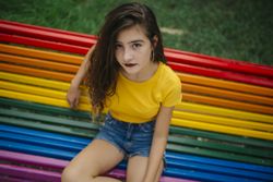 Cheerful woman sitting on rainbow bench