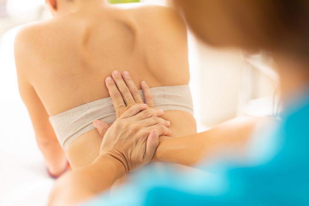 A physiotherapist puts pressure on her patient's back, using manual therapy